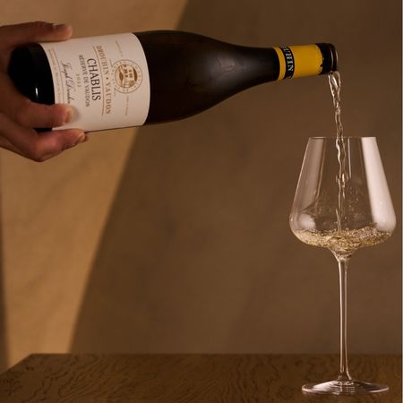 bottiglia di chablis che versa vino bianco in calice